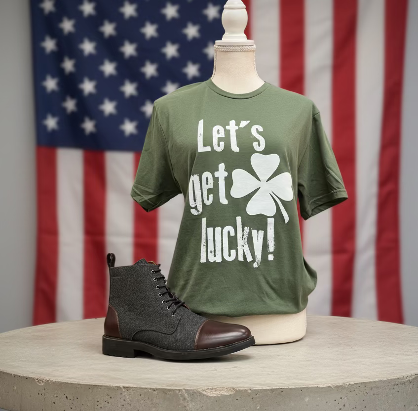 Green t-shirt with 'Let's get lucky!' text and a four-leaf clover on a mannequin, paired with a black and brown shoe.