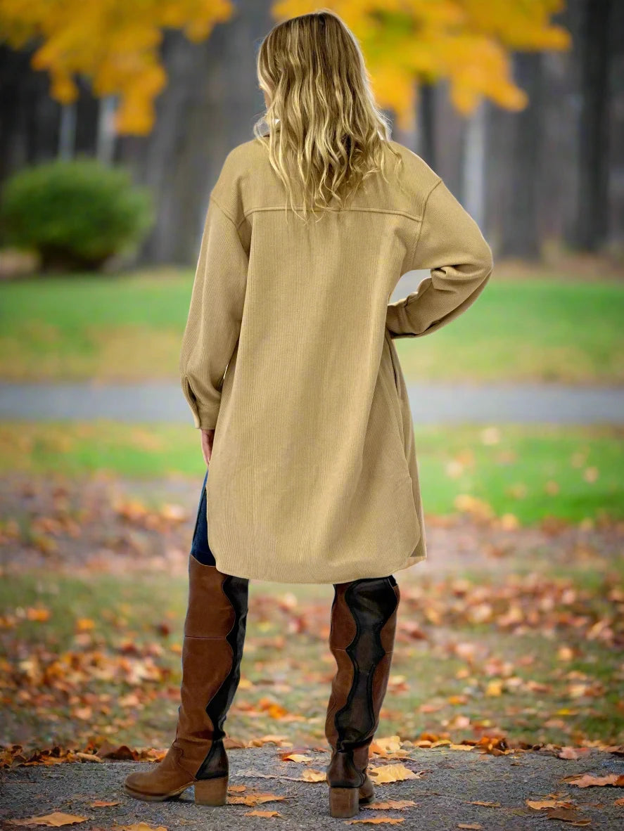 Person wearing a beige coat and brown boots on a white background