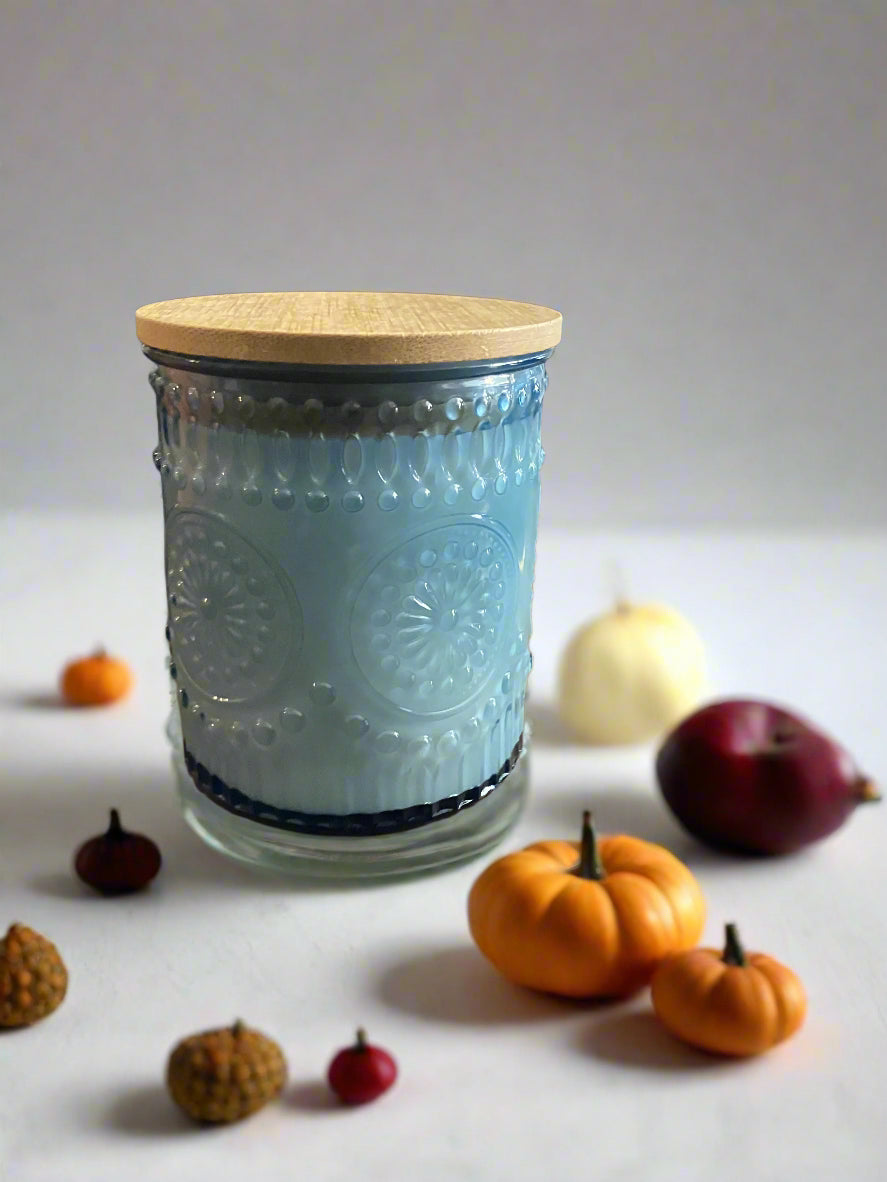 Decorative glass container with wooden lid on a wooden surface